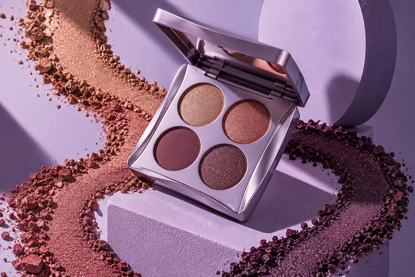 Lilac eyeshadow compact with bronze and plum pigments in a sculptural editorial still life